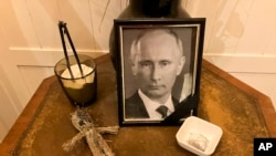 A doll, a bowl of pins and a framed photo of Russian President Vladimir Putin are displayed for customers' use at the Simona pizzeria in central Kyiv on Nov. 17, 2022.