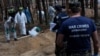 FILE - A war crimes prosecutor stands as experts work at a forest grave site during an exhumation in the town of Izium, in Kharkiv region, Ukraine, Sept. 18, 2022. 