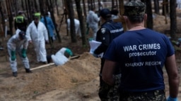 Tužilac za ratne zločine posmatra kako eksperti rade na groblju u šumi tokom ekshumacije u gradu Iziju, u ukrajinskom regionu Harkiv, 18. septebmar 2022. (Foto: REUTERS/Umit Bektas) 