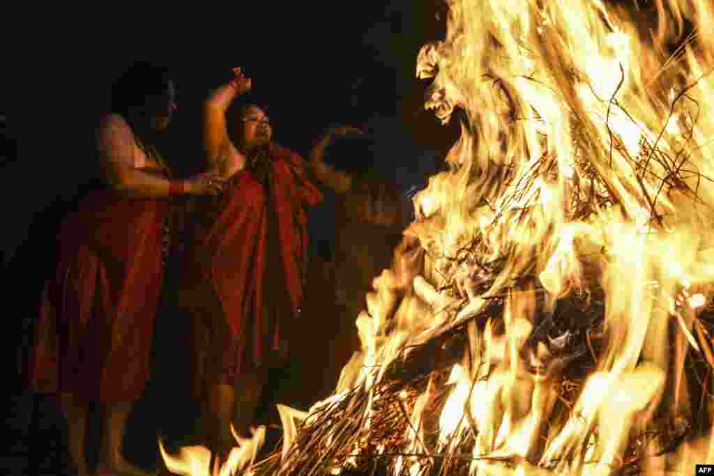 Hindu believers warm themselves around fire after washing themselves in the Shali river during the Swasthani Brata Katha festival, in Sankhu on the outskirts of Kathmandu, Nepal.