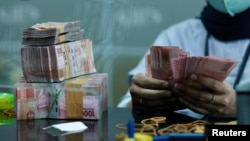 ILUSTRASI - Seorang teller menghitung uang kertas rupiah di money changer di Jakarta, 14 Oktober 2022. (Willy Kurniawan/REUTERS)