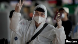 资料照：通过曼谷机场内一名身穿防护服的中国学生举起中国护照。（2020年4月21日）