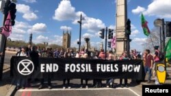 FILE - Environmental activists from the Extinction Rebellion group hold a banner as they block Lambeth Bridge during a Just Stop Oil protest in London, Britain, April 15, 2022. (Extinction Rebellion/Handout via Reuters)