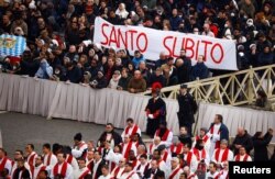 Faithful hold a banner that reads 'Saint now', during the funeral of former Pope Benedict, in St. Peter's Square at the Vatican, Jan. 5, 2023. (REUTERS/Guglielmo Mangiapane)