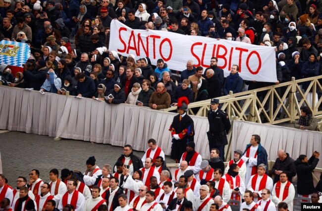 Faithful hold a banner that reads 'Saint now', during the funeral of former Pope Benedict, in St. Peter's Square at the Vatican, Jan. 5, 2023. (REUTERS/Guglielmo Mangiapane)