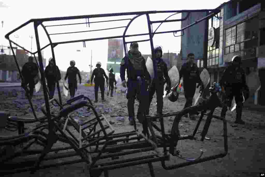 Полицијата оди покрај запалено моторно такси оставено од луѓе кои протестираа против приведувањето на претседателот Педро Кастиљо, на автопатот Панамерикански север во Виру, Перу.