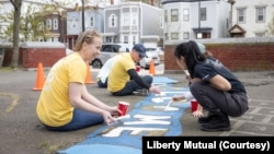 Liberty Mutual employees clean and paint a playground in Boston. The company is among a number of companies in the United States that pay their employees while they volunteer. (Photo courtesy of Liberty Mutual)