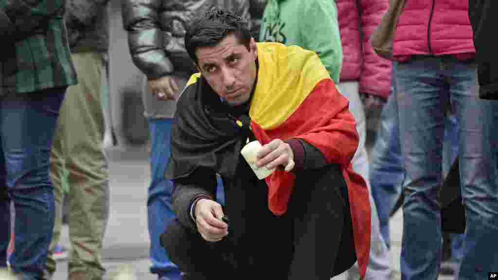 Un homme place une bougie en hommage aux victimes des attentats en Belgique, 23 mars 2016.