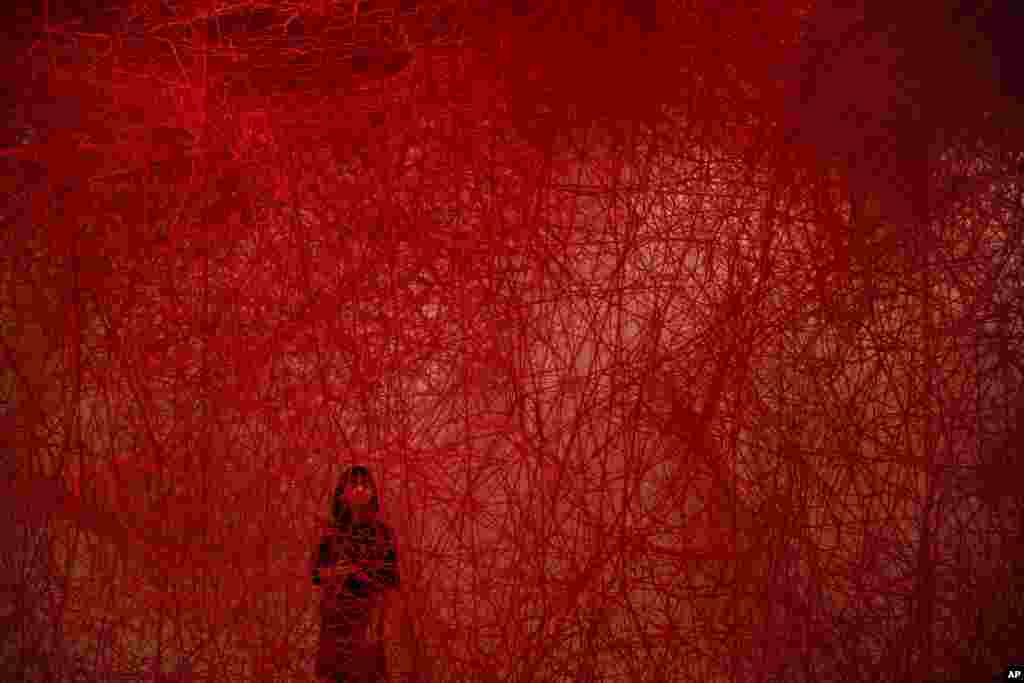A woman looks at Chiharu Shiota's art installation titled "Uncertain Journey" at the Mori Art Museum in Tokyo, Japan.