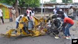 People inspect a damaged tricycle at the site of a bomb explosion, caused by a female suicide bomber in a market in Maiduguri, Nigeria, July 31, 2015. 