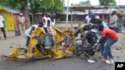 People inspect a damaged tricycle at the site of a bomb explosion, caused by a female suicide bomber in a market, in Maiduguri, Nigeria, July 31, 2015. 