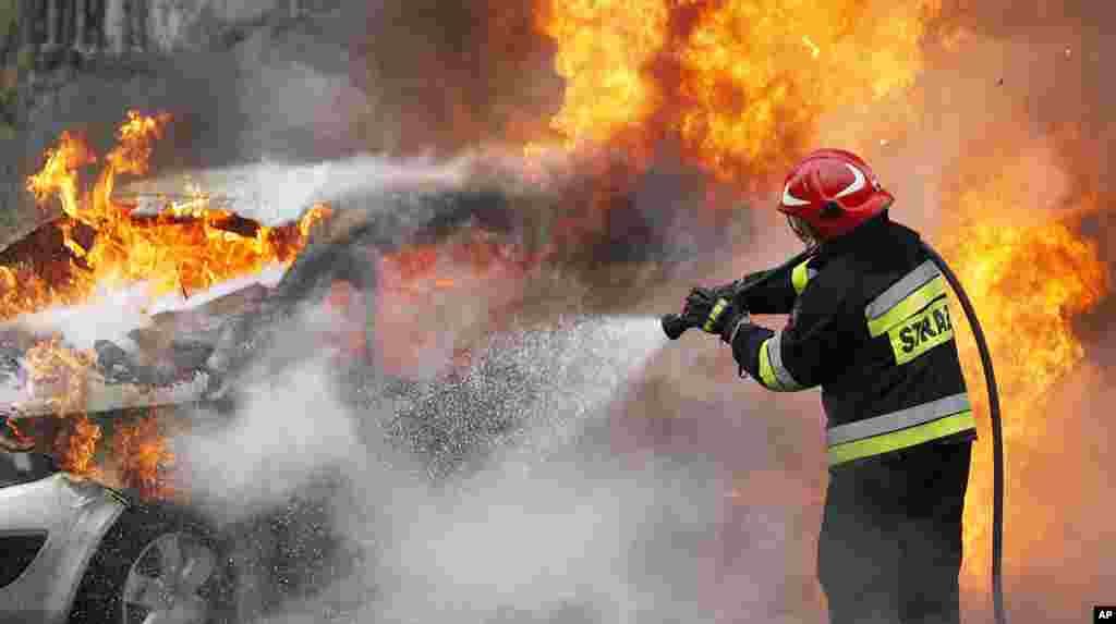 A firefighter extinguishes a burning car on the road leading from the city to the Frederic Chopin airport in Warsaw, Poland. It was not clear what caused the fire in which no one was hurt.