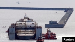 Tàu kéo đẩy tàu Costa Concordia vào cảng Genoa ở miền Bắc Italy, nơi chiếc tàu sẽ được phá bỏ làm phế liệu, ngày 27/7/2014.