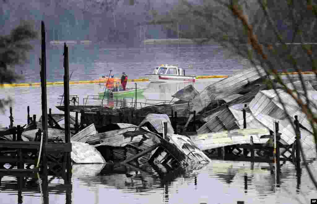 People on boats patrol near the charred remains of a dock following a fatal fire at a Tennessee River marina in Scottsboro, Alabama, USA.