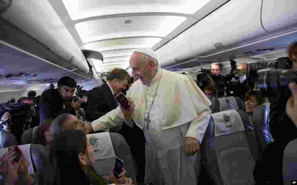Pope Francis greets journalists aboard the papal flight on his way to Amman, Jordan, Saturday, May 24, 2014.