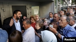 A bank manager tries to explain the situation to hundreds of pensioners queuing outside a National Bank branch in Athens, Greece, July 1, 2015. 