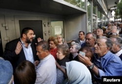 A bank manager tries to explain the situation to hundreds of pensioners queuing outside a National Bank branch in Athens, Greece, July 1, 2015. About one thousand Bank branches around Greece opened on Wednesday to allow pensioners to receive a small part