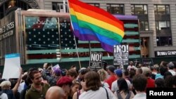 FILE - A rainbow flag flies as people protest U.S. President Donald Trump's announcement that he plans to reinstate a ban on transgender individuals from serving in any capacity in the U.S. military, in Times Square, in New York City, July 26, 2017. 