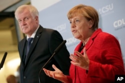 FILE - German Chancellor Angela Merkel, right, and the Governor of the German State of Bavaria, Horst Seehofer, left, address the media during a statement about their talks on the migrant influx in Berlin, Germany, Nov. 3, 2015.