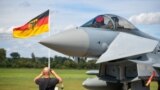 FILE - This file photo taken on Aug. 20, 2020 shows a man taking pictures of an Eurofighter jet of the German Air Force on the tarmac of the German Armed Forces (Bundeswehr) airbase in Noervenich, western Germany. 