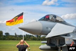 FILE - This file photo taken on Aug. 20, 2020 shows a man taking pictures of an Eurofighter jet of the German Air Force on the tarmac of the German Armed Forces (Bundeswehr) airbase in Noervenich, western Germany.