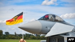 FILE - This file photo taken on Aug. 20, 2020 shows a man taking pictures of an Eurofighter jet of the German Air Force on the tarmac of the German Armed Forces (Bundeswehr) airbase in Noervenich, western Germany.