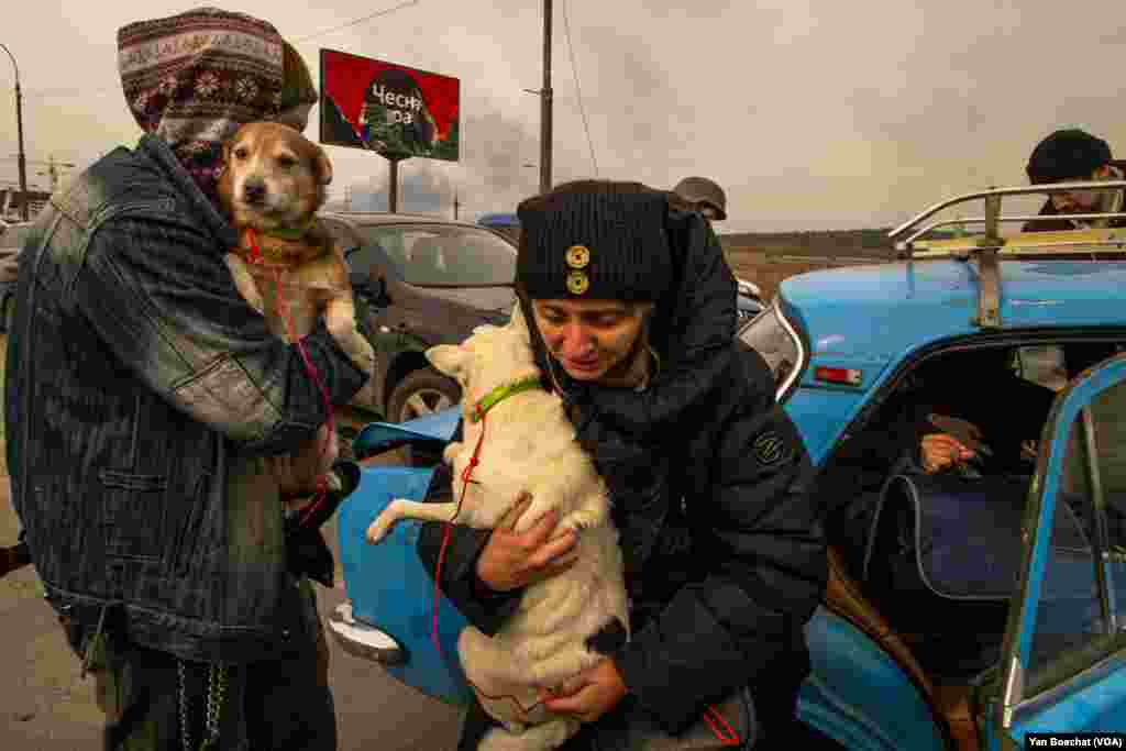 A family and their dogs reach the crossing point between Irpin and Kyiv and leave the battles behind them. Irpin, Ukraine, March 12, 2022. (Yan Boechat/VOA)