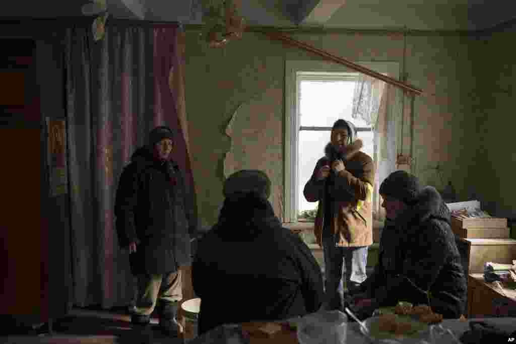 Nina Mikolaivna, de 78 años, a la izquierda, habla con sus vecinos después de que su casa fuera dañada por un bombardeo ruso en Baryshivka, al este de Kiev, Ucrania, el viernes 11 de marzo de 2022. (Foto AP/Felipe Dana)