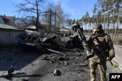 A Ukrainian soldier holds an anti-tank weapon that was used to destroy a Russian armored personal carrier (APC) in Irpin, north of Kyiv, March 12, 2022.