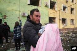 مردی در حال حمل یک نوزاد پس از بمباران زایشگاه و بیمارستان کودکان در شهر محاصره شده مارویپل - ۱۸ اسفند ۱۴۰۰