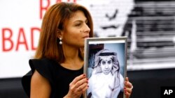 FILE - Ensaf Haidar, wife of Saudi blogger Raif Badawi, shows a portrait of him as he is awarded the Sakharov Prize in Strasbourg, France, Dec. 16, 2015. Badawi was released March 11, 2021, after a decade in prison for criticizing the Saudi conservative religious establishment.