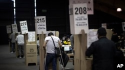 People cast their votes during legislative elections in Bogota, Colombia, Sunday, March 13, 2022. Colombians went to the polls to renew Congress, and also to choose presidential candidates from three political coalitions whose outcome will be key for the next presidential election on May 29. (AP Photo/Ivan Valencia)