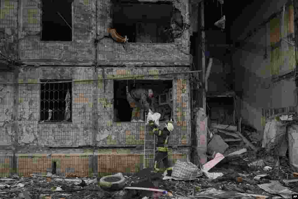 People retrieve belongings from an apartment which was destroyed by an artillery strike in Kyiv, March 14, 2022. Russia&#39;s military forces kept up their punishing campaign to capture Ukraine&#39;s capital with fighting and artillery fire in Kyiv&#39;s suburbs after an airstrike on a military base near the Polish border brought the war dangerously close to NATO&#39;s doorstep.