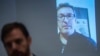 Hong Kong Watch founder Benedict Rogers, right on screen, speaks to the media during a press conference in Hong Kong on April 10, 2018.