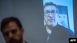 Hong Kong Watch founder Benedict Rogers, right on screen, speaks to the media during a press conference in Hong Kong on April 10, 2018.