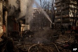 Petugas pemadam kebakaran bekerja di sebuah gedung apartemen yang rusak akibat penembakan di Kyiv, Ukraina, Selasa, 15 Maret 2022. (Foto: AP/Felipe Dana)