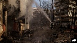 Ukrainian firefighters work in an apartment building after bombing in Kyiv, Ukraine, Tuesday, March 15, 2022. (AP Photo/Felipe Dana)