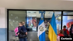 Una mujer ucraniana, con su hijo en brazos, aguarda mientras tramita su entrada al país, en el Aeropuerto Internacional La Aurora, en Ciudad de Guatemala, en la noche del 11 de marzo de 2022. [Foto: Cortesía del Instituto Guatemalteco de Migración]