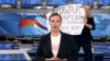 A protester is seen behind an anchorwoman on Russian state TV Channel One, March 14, 2022, in his screen grab taken from YouTube.