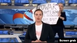 A protester is seen behind an anchorwoman on Russian state TV Channel One, March 14, 2022, in his screen grab taken from YouTube.
