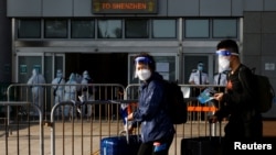 2022年3月14日，在香港爆发新冠毒病期间，戴着口罩和防护罩的旅客通过在深圳湾口岸的中港边境