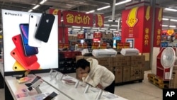 A man browses an iPhone unit on display at a section selling Apple's products together with Chinese made electric appliances at a hypermarket in Beijing, Thursday, May 9, 2019. 