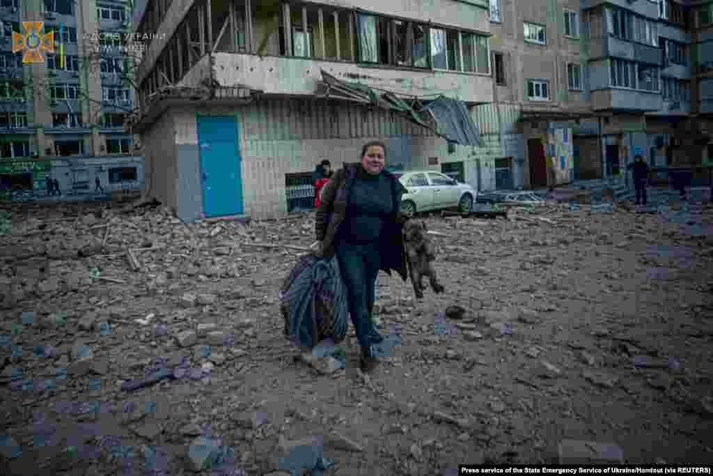 A woman with a dog evacuates from a residential building damaged by shelling in Kyiv in this handout picture released March 16, 2022.