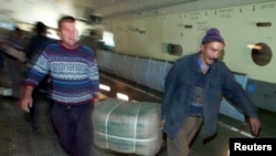 FILE - Uzbek workers carry a pack with blankets delivered from India as they unload a plane in Termez, Dec. 15, 2001. Humanitarian aid for millions of displaced Afghans battling winter cold, disease and hunger were to be distributed through Termez on the border with Afghanistan.