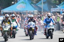 Pembalap Italia Luca Marini (kiri), Andrea Dovizioso (tengah), pembalap Spanyol Alex Rins (kanan), dalam parade di Jakarta, Rabu, 16 Maret 2022. Moto GP akan digelar di Mandalika, Lombok,18 -20 Maret 2022.(Foto AP/Achmad Ibrahim)