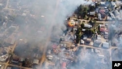 File - Smoke arises from burning buildings in Waraisuplia village in Kayah State, Myanmar where Myanmar’s military is targeting civilians in air and ground attacks, Feb. 18, 2022.