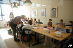 Ukrainian teacher Tatyana Gubskaya, center, teaches a class of children from the Ukraine in Berlin, Germany, Monday, March 21, 2022. (AP Photo/Markus Schreiber)