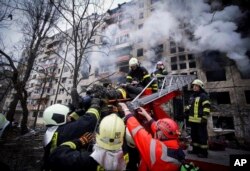 Petugas pemadam kebakaran mengevakuasi seorang pria dari gedung apartemen yang terkena tembakan di Kyiv, Ukraina, Senin, 14 Maret 2022. (Foto: via AP)