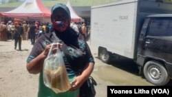 Ibu Dinem (59) memperlihatkan minyak goreng yang dibeli di pasar murah yang diselenggarakan oleh Dinas Perindustrian dan Perdagangan Provinsi Sulawesi Tengah. Selasa (15/3/2022) (Foto: VOA/Yoanes Litha)