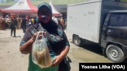 Ibu Dinem (59) memperlihatkan minyak goreng yang dibeli di pasar murah yang diselenggarakan oleh Dinas Perindustrian dan Perdagangan Provinsi Sulawesi Tengah. Selasa (15/3/2022) (Foto : VOA/Yoanes Litha)